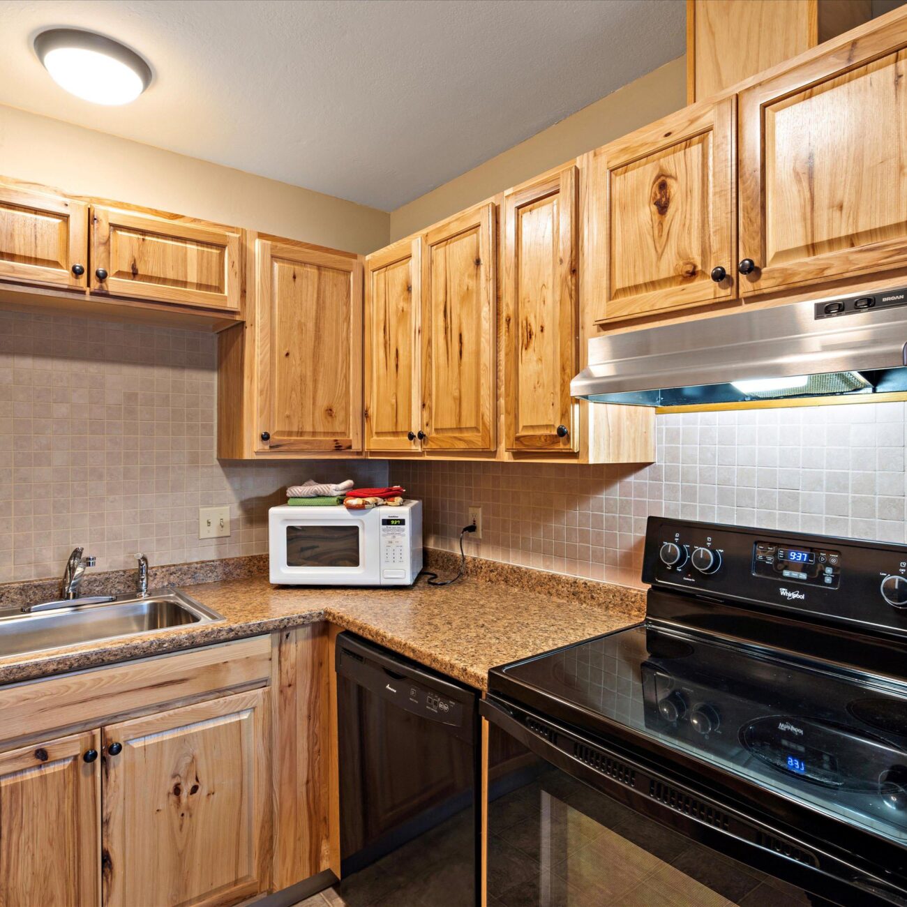 A contemporary kitchen with stove, microwave, sink, and lots of cabinets