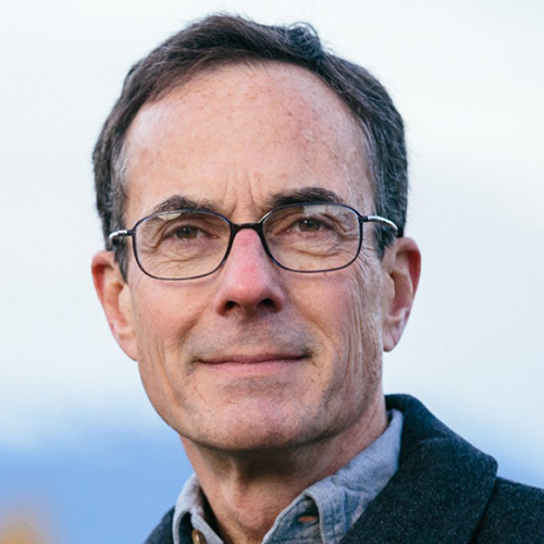 Headshot of a man with short brown hair wearing glasses